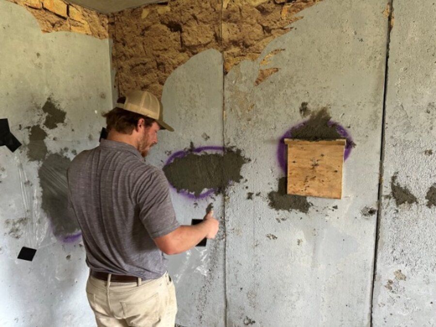 Amidon technician troweling mixed ballistic concrete repair material into a prepared patch on a shoot house wall