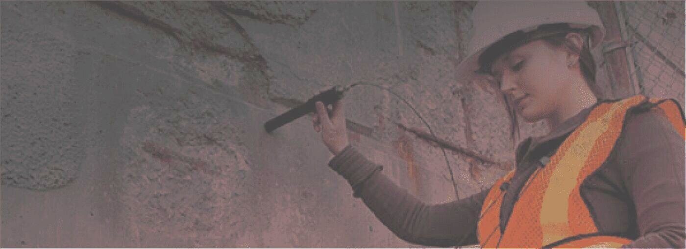 Amidon technician inspecting ballistic concrete wall damage during a live-fire training facility site visit