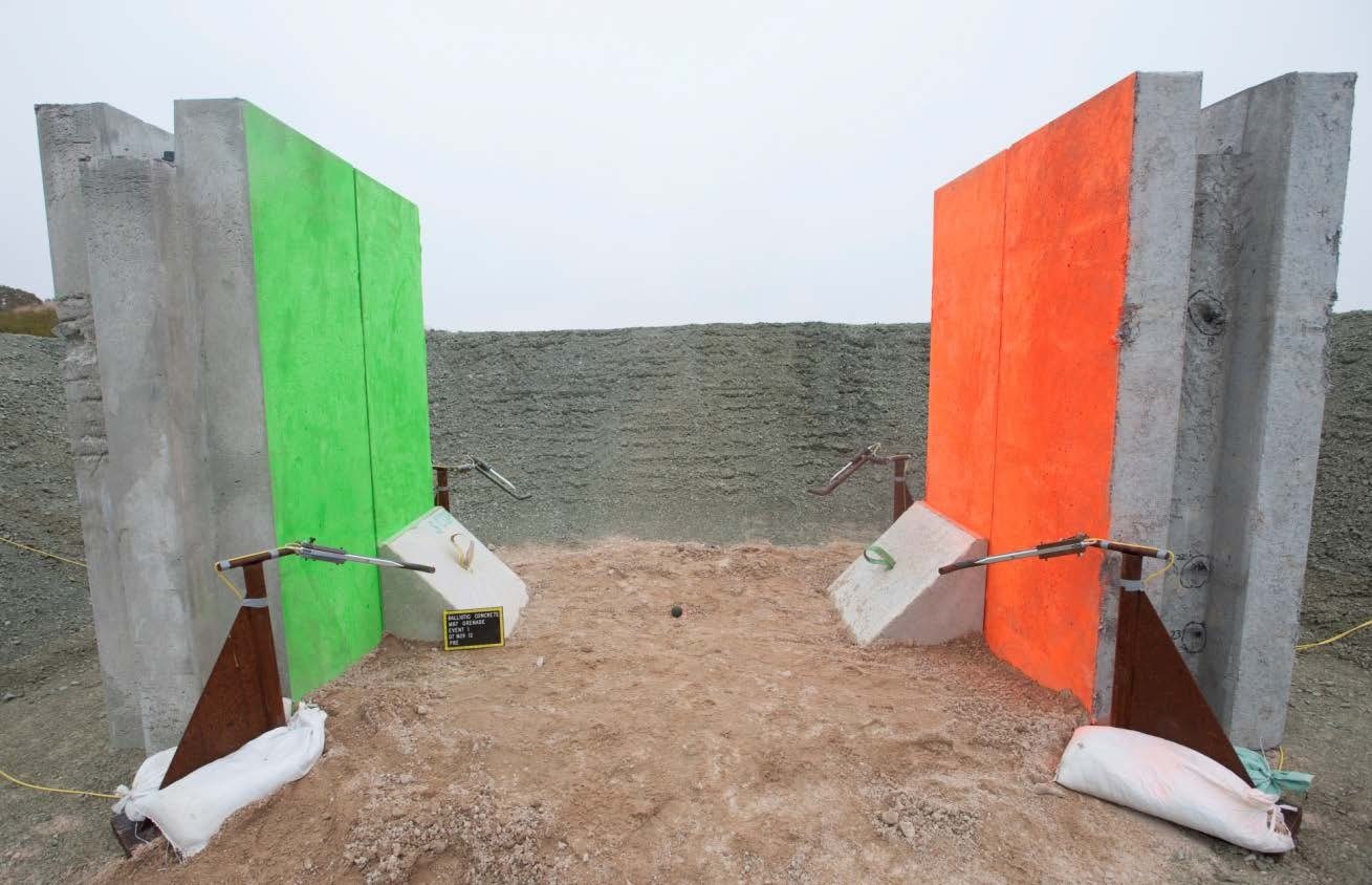 A bermed fragmentation-grenade test area with ballistic concrete wall panels flanking the blast zone