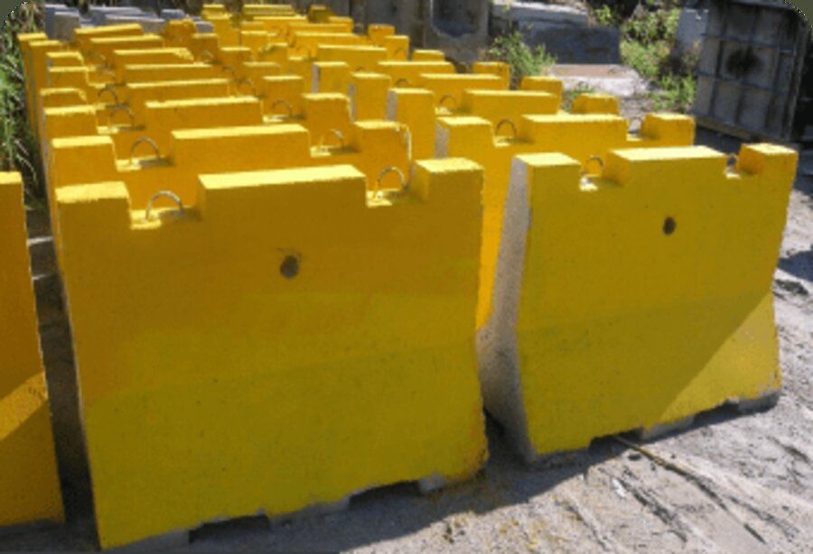 Row of yellow Amidon Ballistic Concrete modular security barriers staged outdoors.