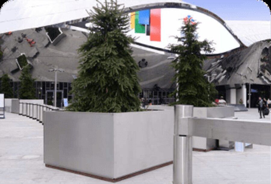 Outdoor plaza combining ballistic concrete planters and decorative landscaping near a public venue.
