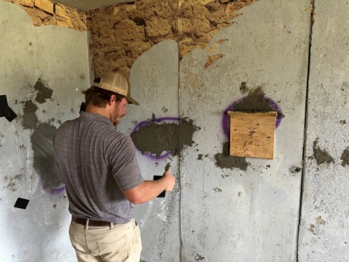 Amidon technician troweling ballistic concrete repair material into a prepared patch cavity on a shoot house wall