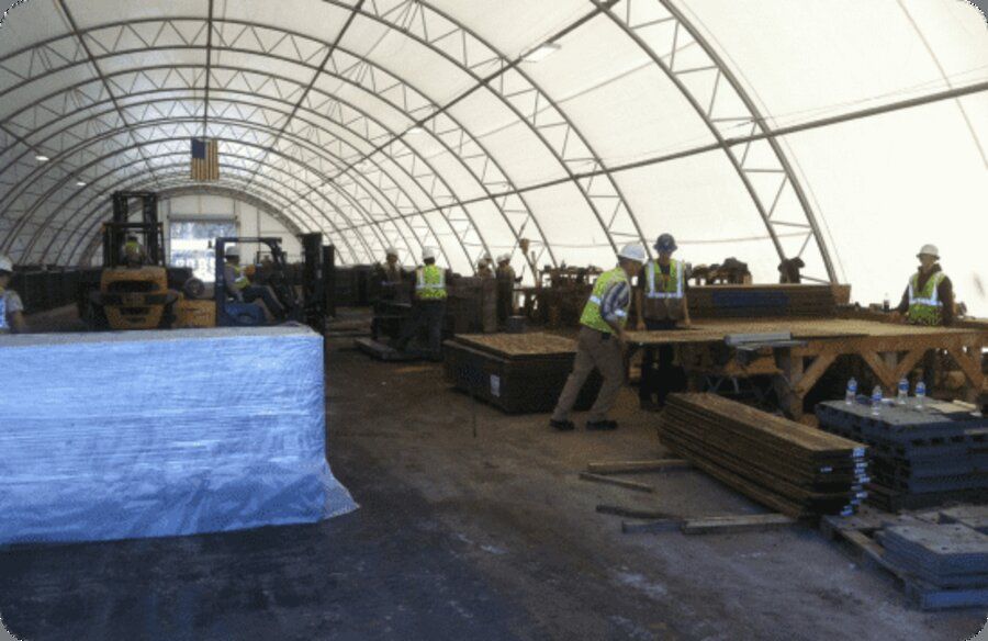 Crew fabricating ballistic concrete panels inside a covered production facility