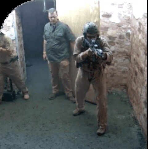 Trainees conducting close-quarters battle movement through a shoot house corridor during live-fire training