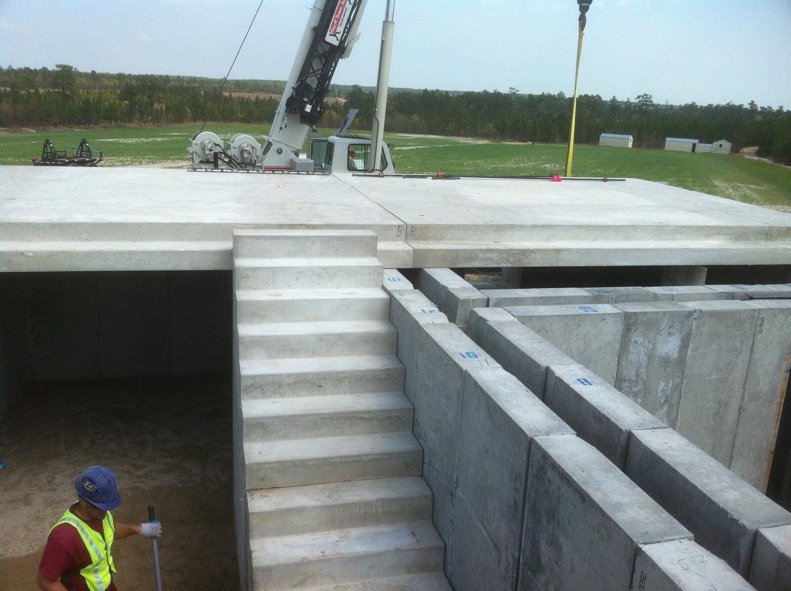 Crane lowering a precast ballistic concrete panel into place on a second-story installation at a training facility